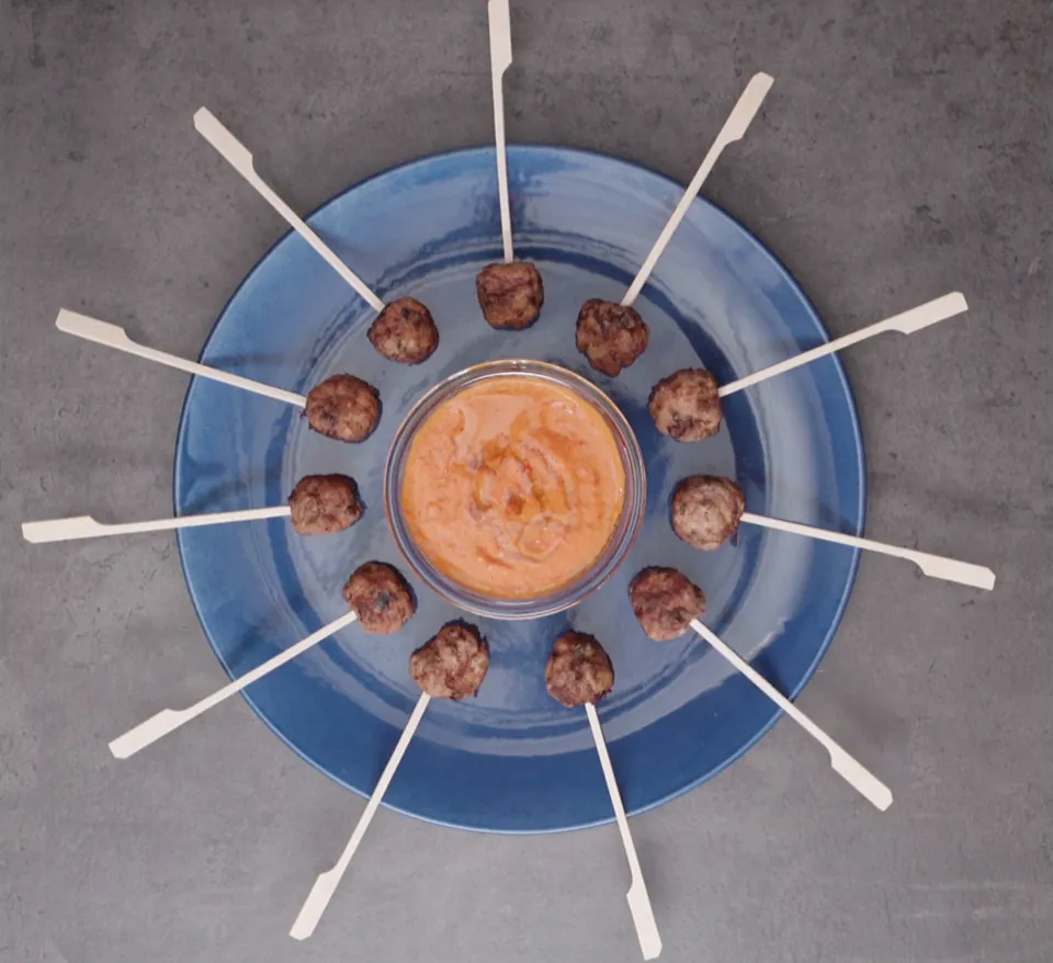 Meatball lollipops with a creamy red pepper sauce